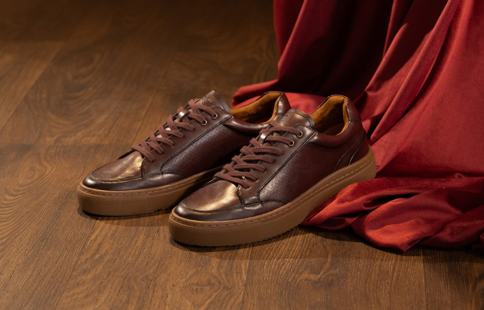 Shop Stacy Adams casuals featuring the Dorian sneaker in burgundy next to a red drape. 
