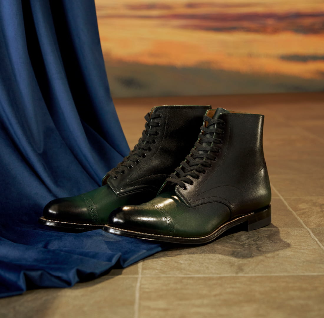 Shop Stacy Adams classics featuring the Madison boot in green ombre next to a blue curtain.