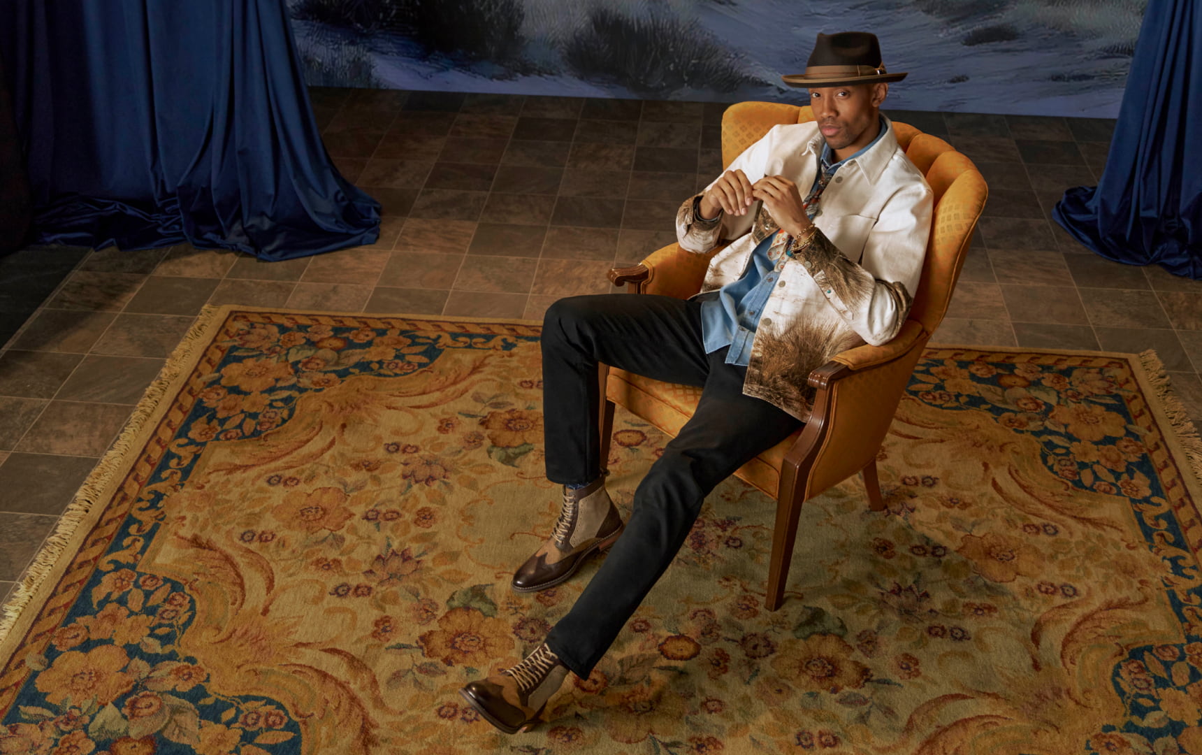 Shop Stacy Adams boots featuring the Finnegan wingtip boot on a man sitting in a gold chair. 