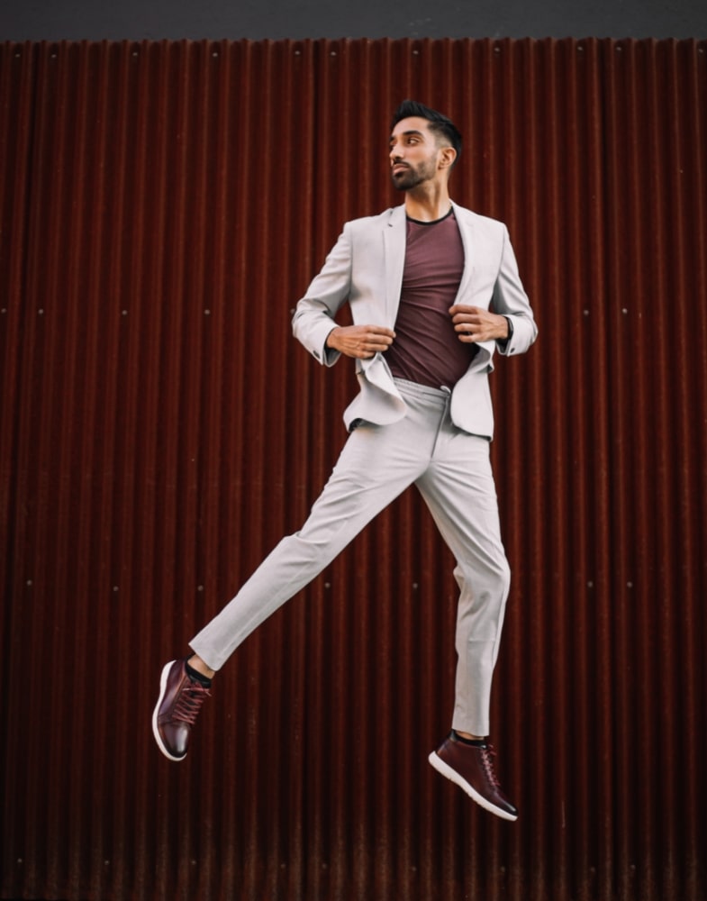 Image of social media influencer Gurneet Mangat jumping while wearing the Harlow Cap Toe Mid Lace Up in Burgundy Milled.