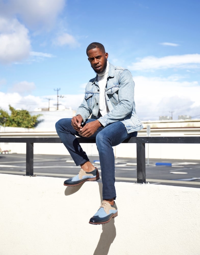 Image of social media influencer Chidi Ezemma sitting on a ledge wearing the Kitt Wingtip Oxford in Blue Multi.