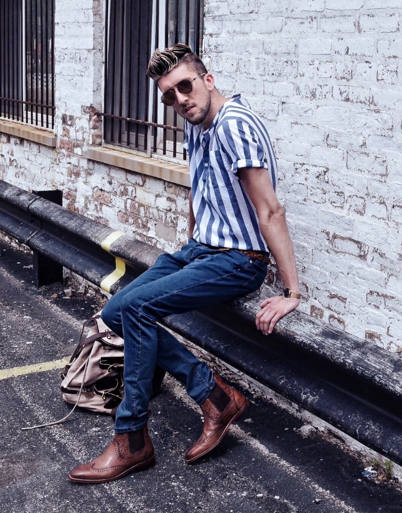 Image of social media influencer Thomas Trust wearing the M2 Wingtip Chelsea Boot in Cognac while sitting on a car railing.