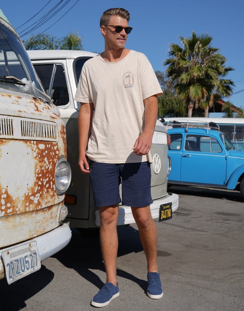 Image of social media influencer Drew Mellon from the duo "Beach Byrds" wearing the Eli Plain Toe Oxford in Cream while sitting on steps. 