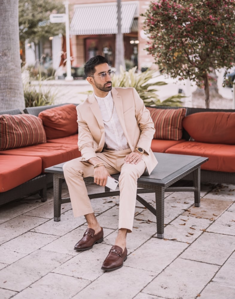 Image of social media influencer Gurneet Mangat sitting down while wearing the Pomery Moc Toe Bit Slip On in Cognac.