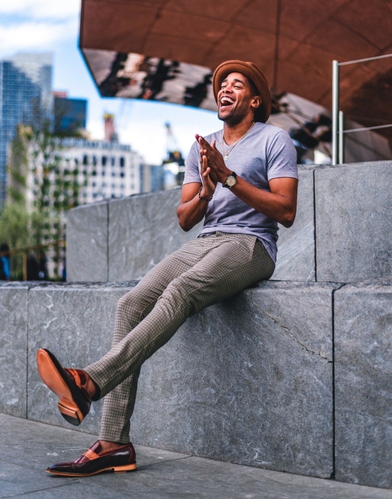 Image of social media influencer and Harlem Globetrotter Brawley Chisholm wearing the Sanhurst Moc Toe Penny Slip On in Brown Multi while laughing in NYC.