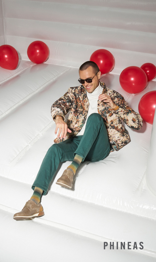 Shoes for Men view all category. Image features a man wearing the Phineas in a white bounce house with red balls.
