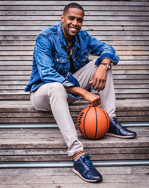 Image of social media influencer and Harlem Globetrotter Brawley Chisholm wearing the Axel Moc Toe Lace Up in Navy while sitting on the steps with a basketball.