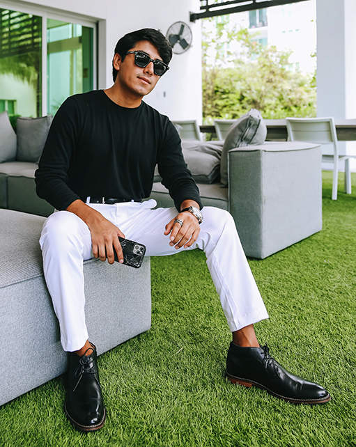 Image of social media influencer Marco Arrieta sitting on a couch wearing the Fraiser Plain Toe Chukka Boot in Black.